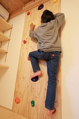 ロフト下の壁に設置されたボルダリングウォールで、遊ぶお子さん。楽しい遊び場に。