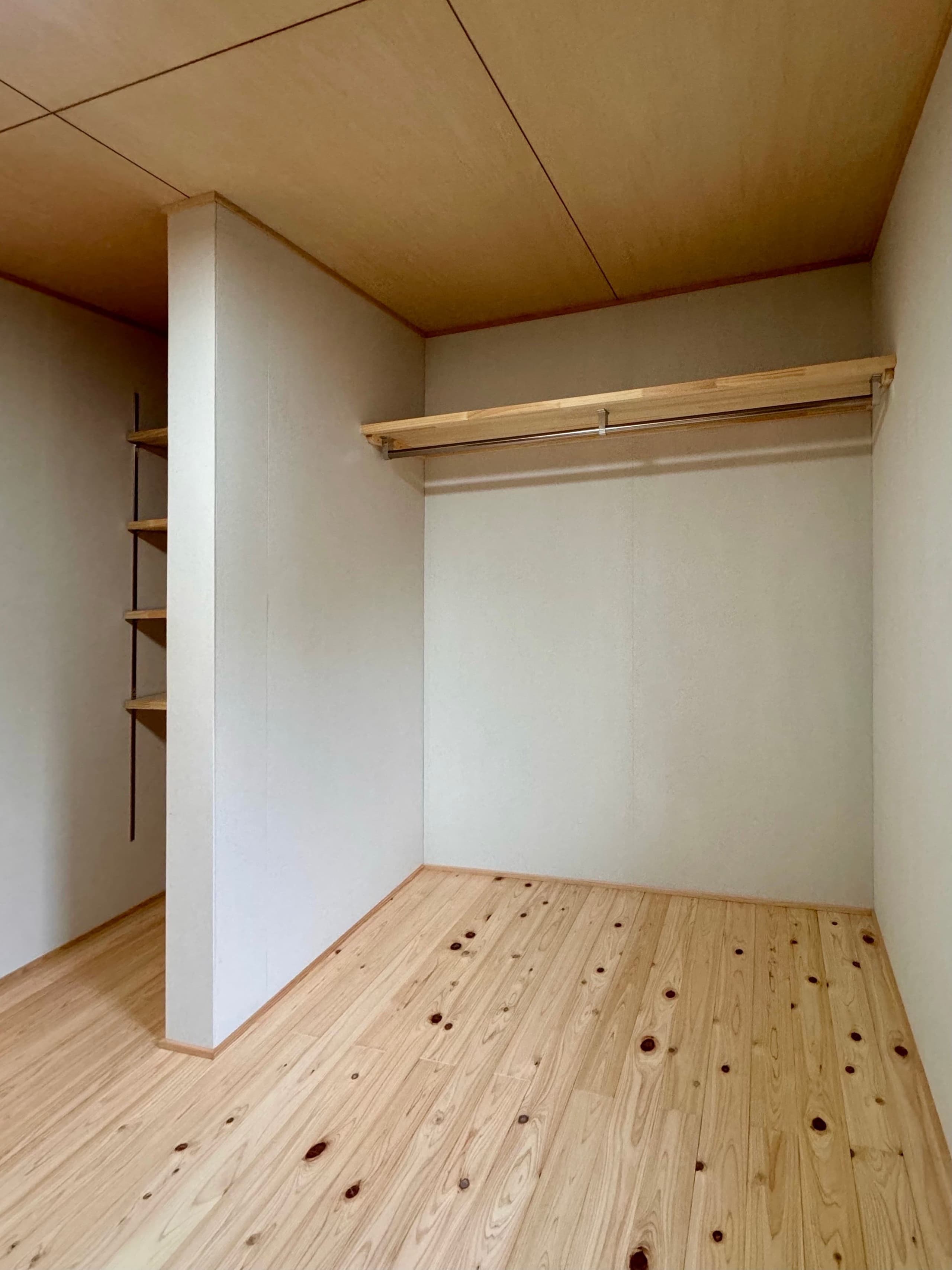 木製の棚やハンガーパイプを備えたウォークインクローゼット